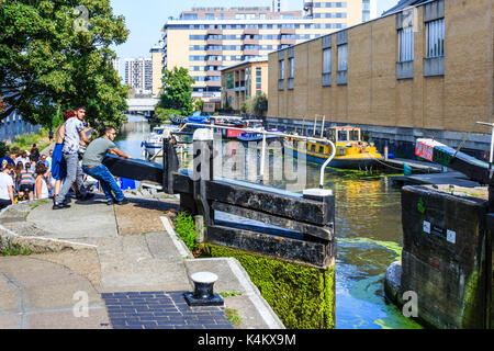 Deux jeunes hommes et une femme ouvrant les portes à verrouillage de Sturt, Regent's Canal, Islington, Londres, Royaume-Uni Banque D'Images