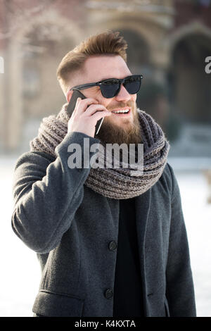 Homme debout en ville pendant l'heure d'hiver et d'avoir une conversation téléphonique nice Banque D'Images