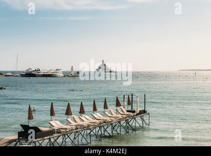 Rangées de empty beach lounges à juan les pins, france avec super yachts dans l'arrière-plan Banque D'Images