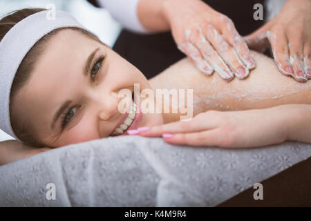 Femme couchée à l'esthéticienne massage Gommage sucre exfoliantes pendant Banque D'Images