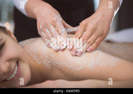 Femme couchée à l'esthéticienne massage Gommage sucre exfoliantes pendant Banque D'Images