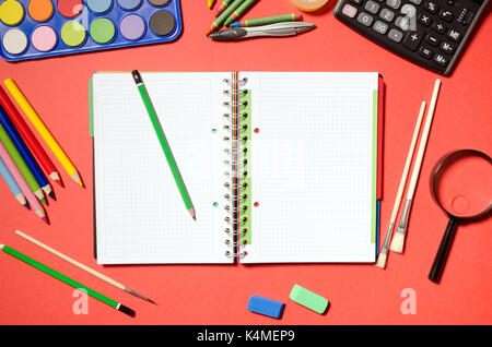 Blank notepad avec l'école et les fournitures de bureau, fond rouge. Stationery Office desk top voir l'école table concept étudiant Banque D'Images