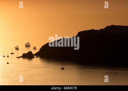 Coucher de soleil sur la mer avec des bateaux et les falaises en silhouette près de Oia, à partir d'Imerovigli, Santorini, Cyclades, îles grecques, Grèce, Europe Banque D'Images