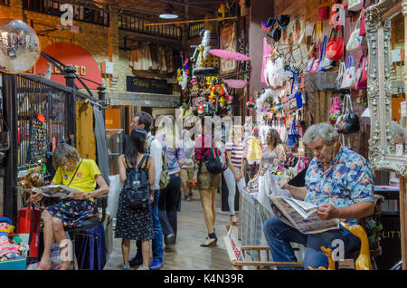 Les propriétaires de décrochage s'asseoir et lire les journaux alors que les clients passent, étals de navigation. d'équitation market, marché de Camden, Londres Banque D'Images