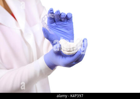 Gros plan des mains de médecins dans les gants en silicone protège dents holding. Banque D'Images
