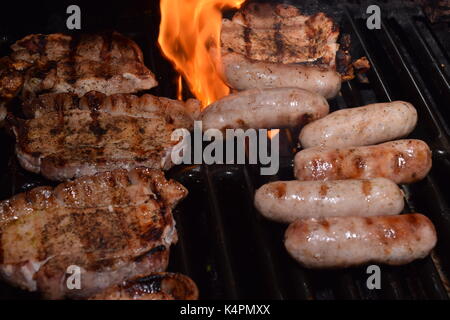 Saucisses fraîches et les côtelettes d'agneau grillées sur un barbecue Banque D'Images