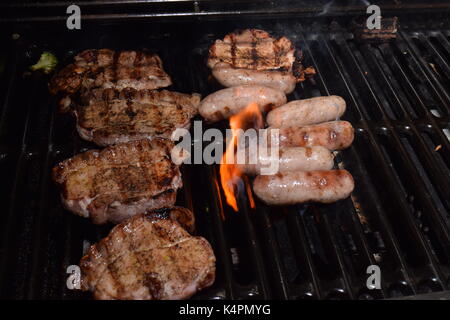 Saucisses fraîches et les côtelettes d'agneau grillées sur un barbecue Banque D'Images