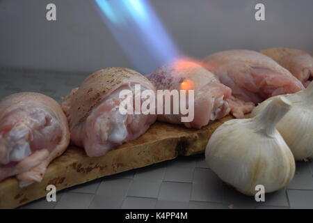 Cuisses de poulet crus sur une planche en bois avec de l'ail Banque D'Images