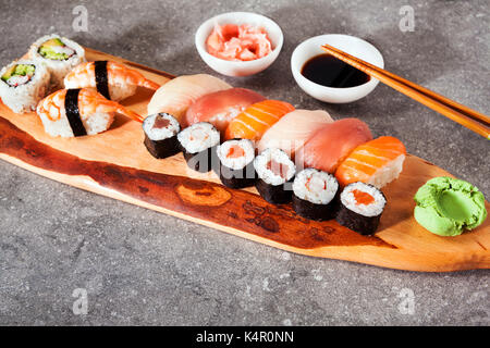 Différents types de sushis servis sur un plat avec de la sauce soja, wasabi et gingembre mariné. Banque D'Images