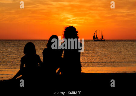 La mère et les deux filles regarder le coucher du soleil à Sand Key Park, Clearwater Beach, Floride USA. Banque D'Images