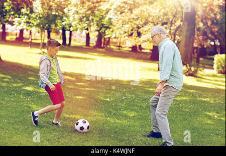 Vieil homme et garçon jouant au football au parc d'été Banque D'Images
