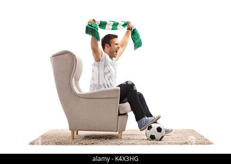 Heureux fan de foot avec un ballon de football et un foulard assis dans un fauteuil cheering isolé sur fond blanc Banque D'Images