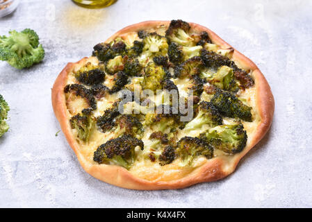 Pizza avec brocoli et fromage sur fond noir en lumière Banque D'Images