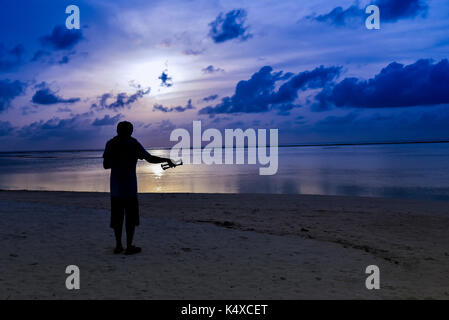 L'homme silhouette le drone de fonctionnement par télécommande sur la plage au Maldives island Banque D'Images