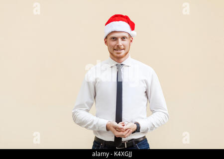 La réussite des jeunes adultes le gingembre businessman looking at camera and smiling. studio shot, léger fond orange Banque D'Images