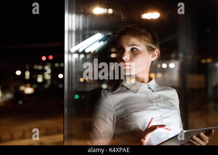 Businesswoman with tablet travailler tard dans la nuit. Banque D'Images