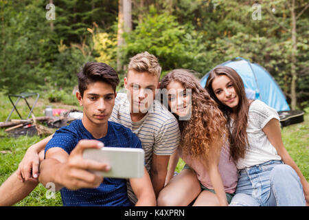 Les adolescents en face de la tente du camping en forêt. Banque D'Images