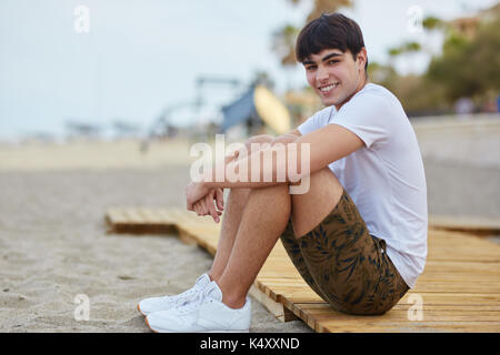 Portrait of young man sitting on beach smiling Banque D'Images
