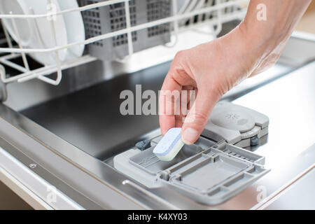 Close up of woman putting tablette de détergent dans l'eau de vaisselle Banque D'Images
