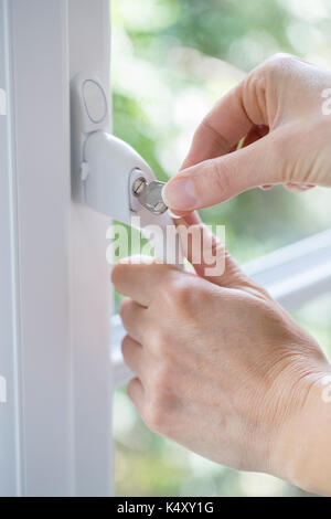 Close Up of Woman en tournant la clé dans la serrure de la fenêtre Banque D'Images