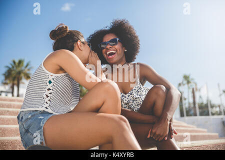 Portrait de jeune femme chuchoter à son rire ami Banque D'Images