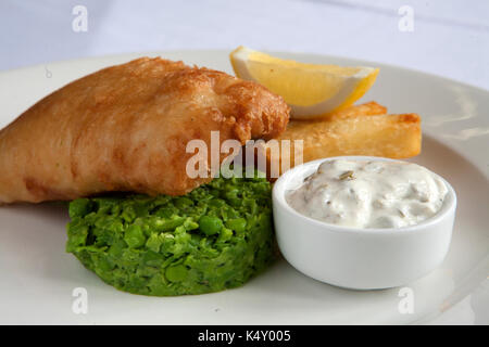 Battered fish and chips avec petits pois et sauce tartare sur une assiette Banque D'Images