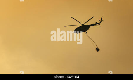 Vol en hélicoptère pompier portant un seau d'eau Banque D'Images