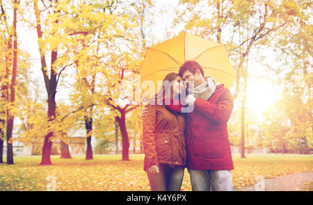 L'amour, relation, saison, famille et personnes concept - couple heureux avec umbrella walking in autumn park Banque D'Images