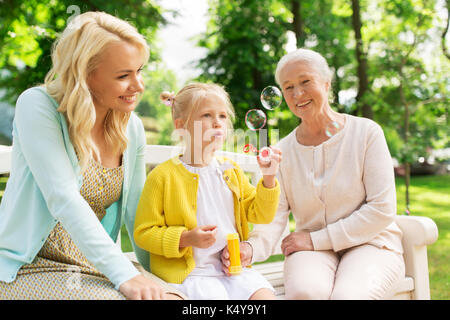 Happy Family blowing soap Bubbles at park Banque D'Images