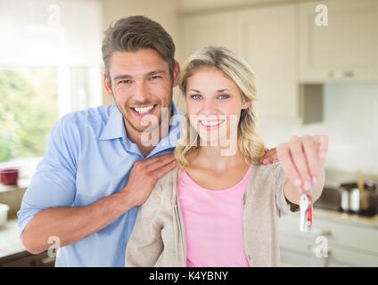 Digital composite of Couple Holding key in kitchen Banque D'Images