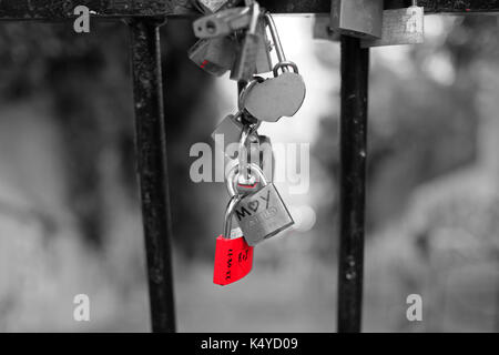 Love locks attachées à des garde-corps par des couples dans l'amour, à Montmartre, Paris, l'un est rouge sur un fond noir et blanc Banque D'Images