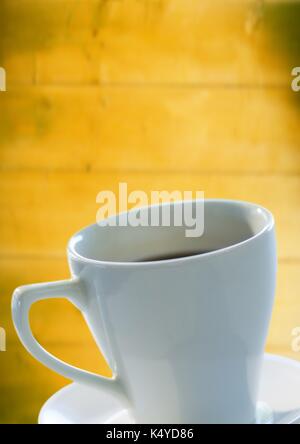 Digital composite de blanc tasse à café et soucoupe contre panneau jaune floue Banque D'Images