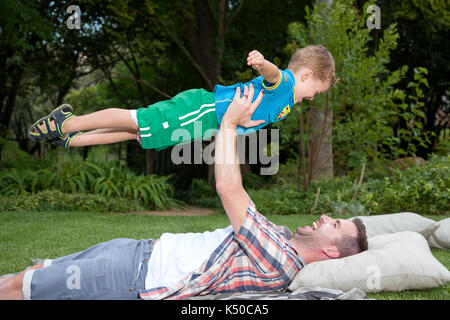 Père jouant de l'avion avec son fils dans le jardin Banque D'Images Père jouant de l'avion avec son fils dans le jardin Banque D'Images