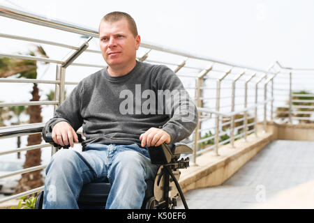 L'homme en fauteuil roulant se trouve près de la balustrade Banque D'Images