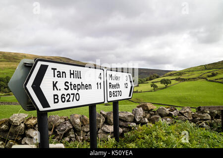 Signes sur la B6270 vers Tan Hill, Kirkby Stephen, Muker et Reeth avec un paysage agricole typique du Yorkshire derrière, Keld, Swaledale, YOR Banque D'Images