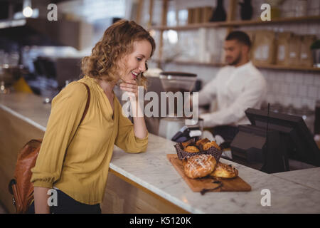 Souriante jeune femme services à la recherche de nourriture pour servir au conseil le comptoir à café Banque D'Images