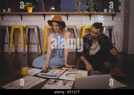 Les jeunes designers travaillant avec des feuilles sur le plancher du coffee shop Banque D'Images