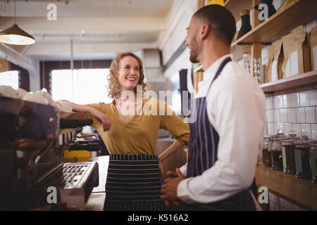 Jeune serveur serveuse souriante et permanent par la machine à expresso au café Banque D'Images