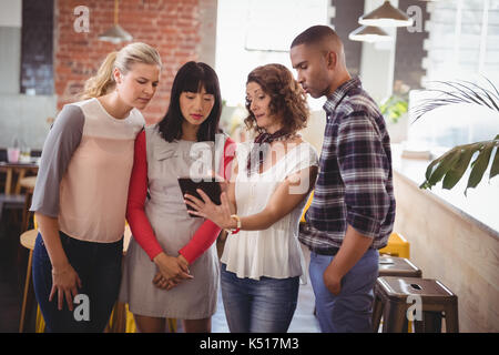 Woman showing digital tablet de jeunes amis tout en se tenant au coffee shop Banque D'Images