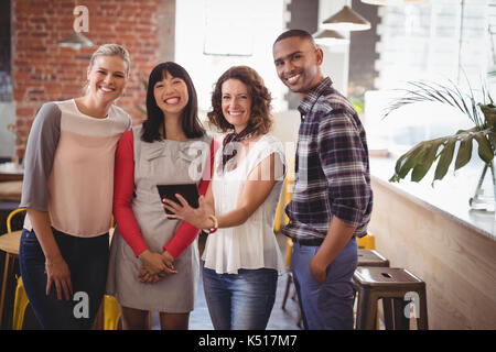 Portrait of young friends standing with digital tablet at coffee shop Banque D'Images