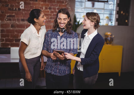 Cheerful young friends standing with digital tablet at coffee shop Banque D'Images