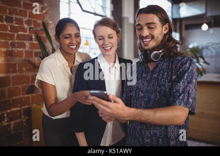 Jeune homme montrant smartphone pour amies tout en se tenant au coffee shop Banque D'Images