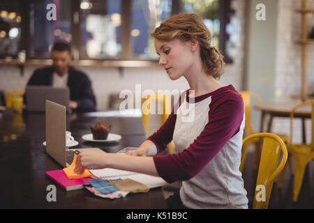 Certains jeunes femmes designer assis avec des ordinateurs portables et des documents at table in coffee shop Banque D'Images