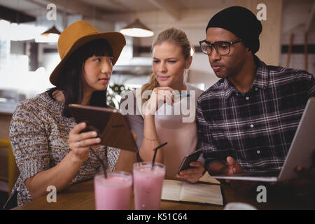 Young woman showing digital tablet à vos amis tout en étant assis à table dans un café Banque D'Images