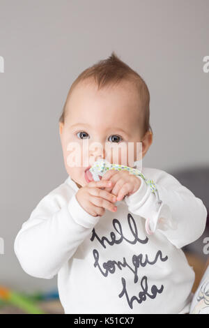 8 mois bébé fille portant son suce de sa bouche et de le sucer Banque D'Images