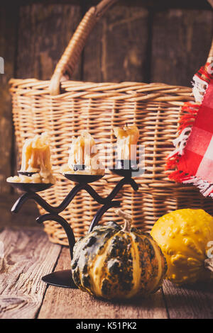 Décorations accueil chaleureux de l'automne. Nature morte avec panier en osier, bougies, mini potirons et red-vérifié serviette dans un style rustique Banque D'Images