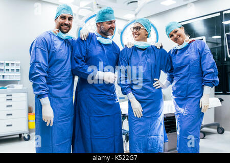 Portrait de l'équipe de chirurgien en salle d'opération permanent. Heureux travailleurs médicaux en chirurgie, dans l'uniforme dans l'exploitation du théâtre. Banque D'Images