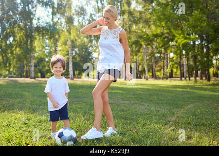 Une mère joue avec son fils dans la balle dans le parc. Banque D'Images