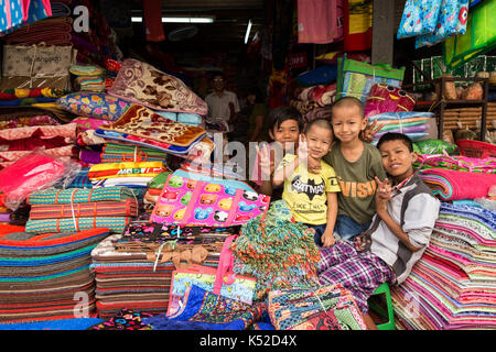 Quatre jeunes garçons heureux à un décrochage des marchandises à la zegyo (également connu sous le nom de zay cho) marché à Mandalay, Myanmar (Birmanie). Banque D'Images