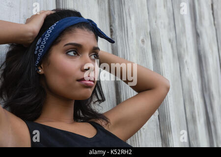 Young woman with hand in hair contre mur en bois Banque D'Images